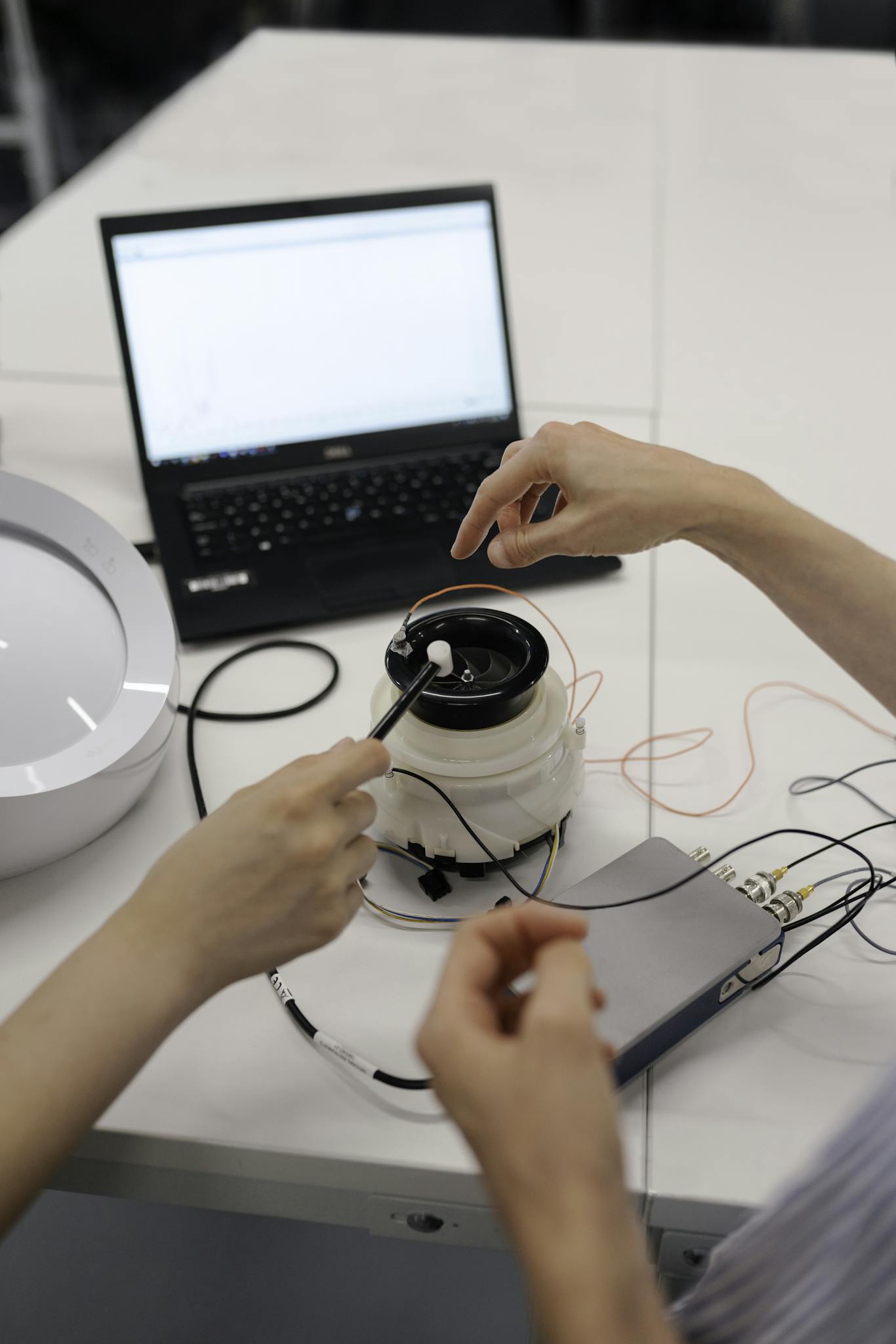 Engineers working on electronic prototype testing with laptop and equipment in a lab.